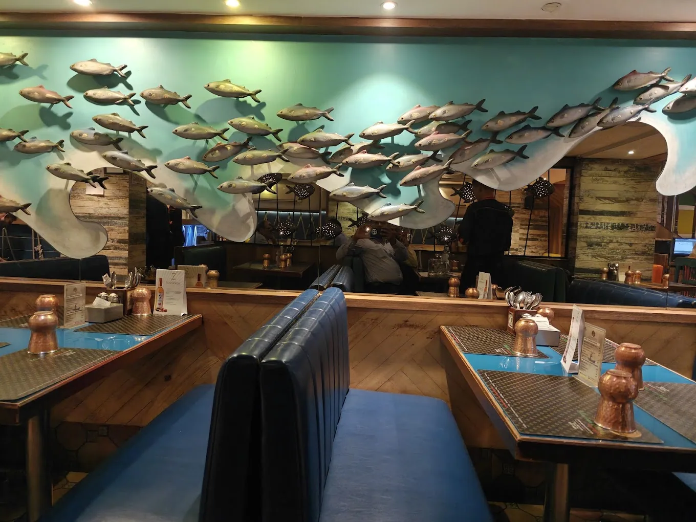 A school of metal fish on a teal wall