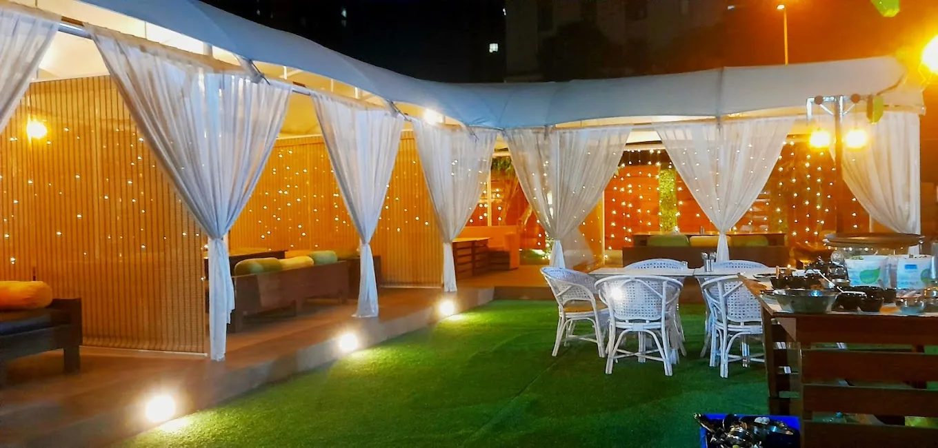 A lawn dressed with white drapes and fairy lights at night