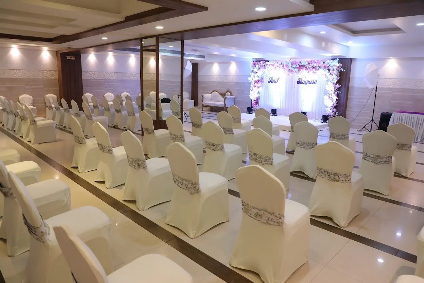 A floral stage set before white chairs