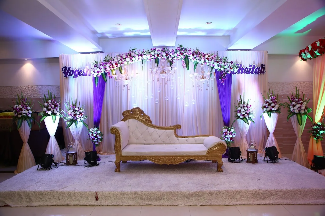 A wedding stage with a gold sofa under purple lighting